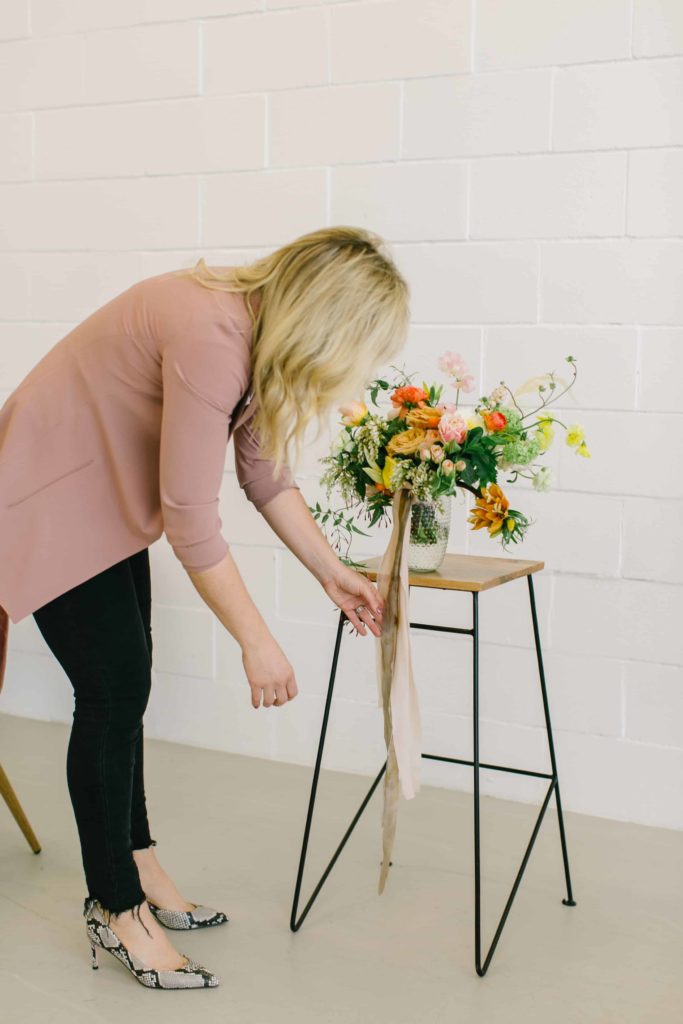 Wedding florist arranges bouquet on a stool