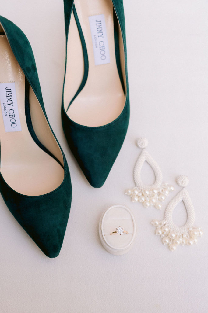 Suede green wedding shoes on a gray backdrop with jewelry