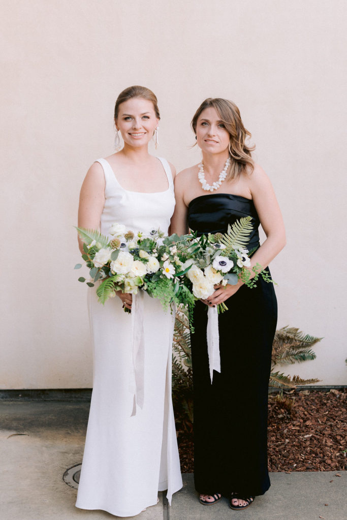 Bride and mother of the bride pose with green and white wedding flowers