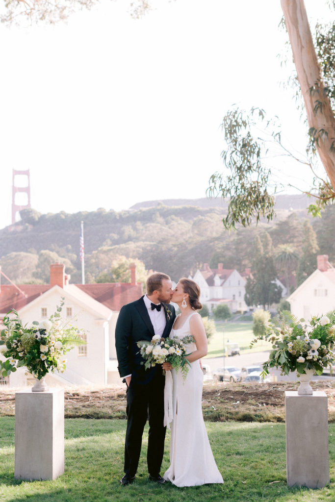 Fern wedding bouquet held by a couple as they kiss with the San Francisco Bay Bridge in the background