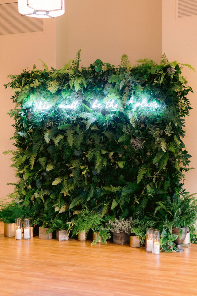 Greenery wall backdrop at a wedding with neon text